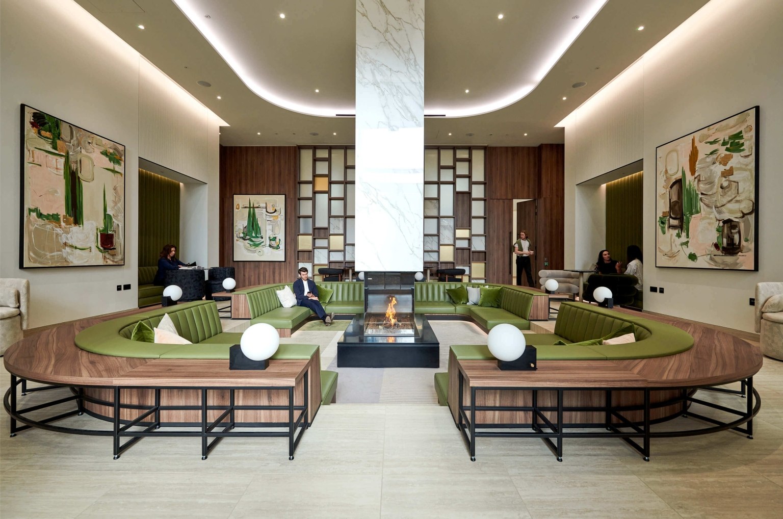 The residents’ lobby with a fireplace and green sofas at White City Living
